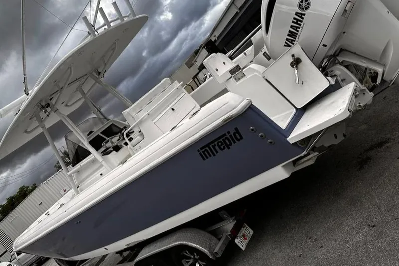 Slide: The Image of 2004 Intrepid 300 Center Console boat with Yamaha engine on trailer, under cloudy sky. - 0