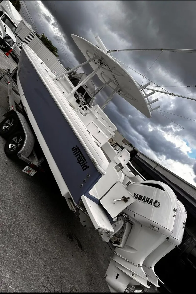 Slide: The Image of 2004 Intrepid 300 Center Console boat with Yamaha engines on a trailer under cloudy skies. - 1
