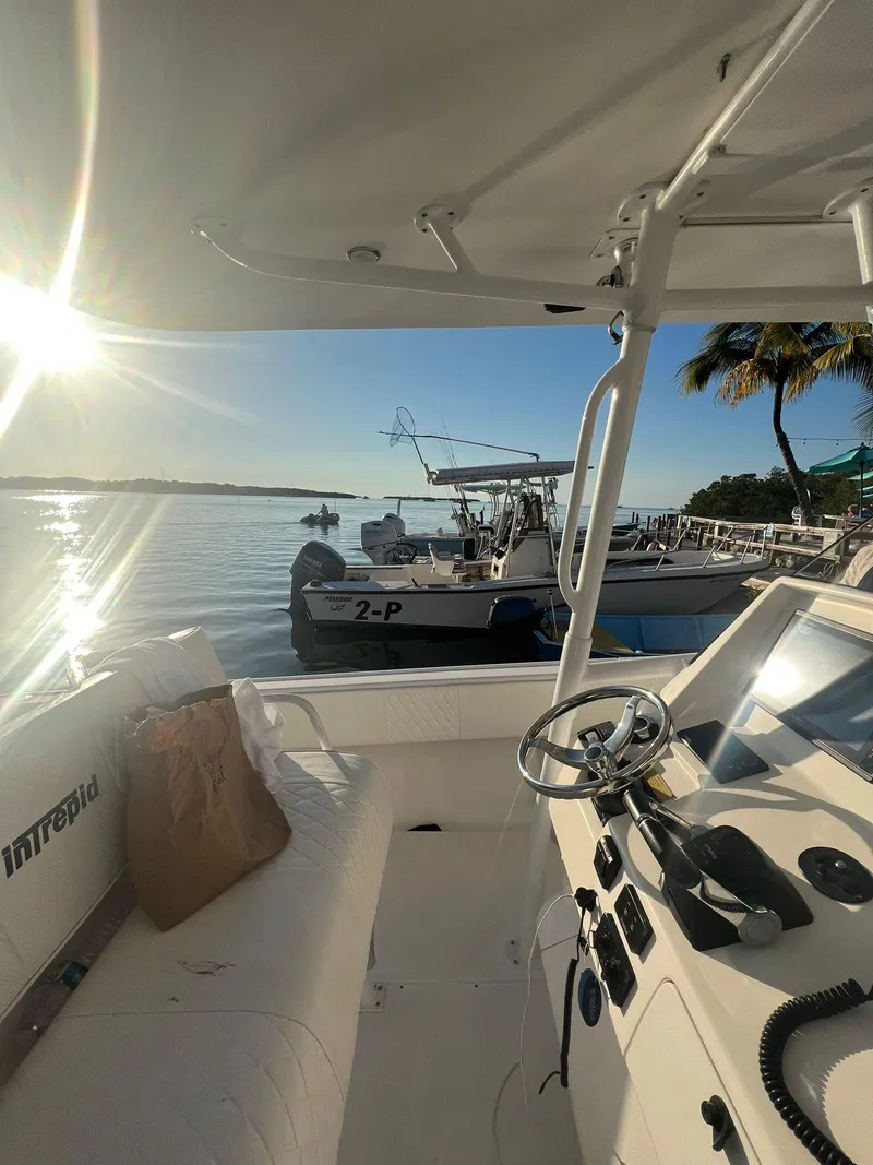 Slide: The Image of 2004 Intrepid 300 Center Console boat docked at sunset, featuring steering controls and a serene waterfront view. - 4