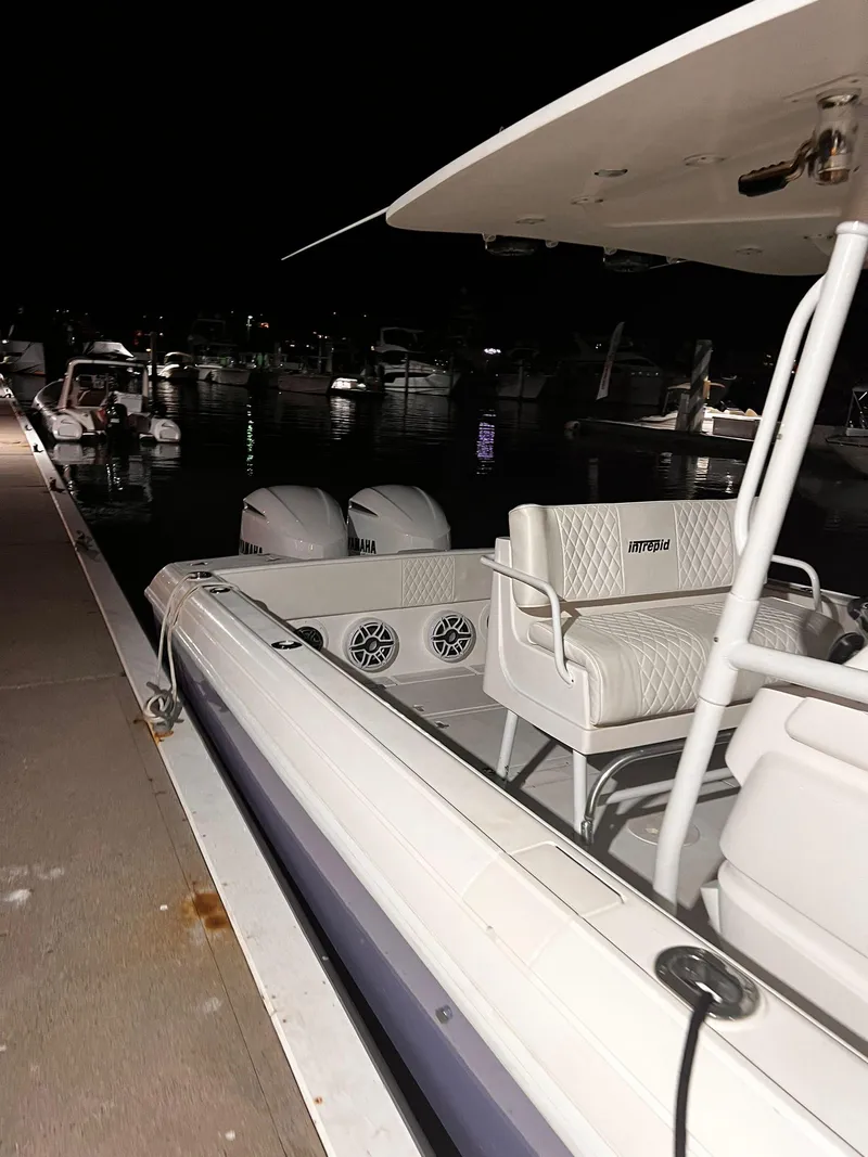 Slide: The Image of 2004 Intrepid 300 Center Console boat docked at night with visible seating and twin engines. - 6