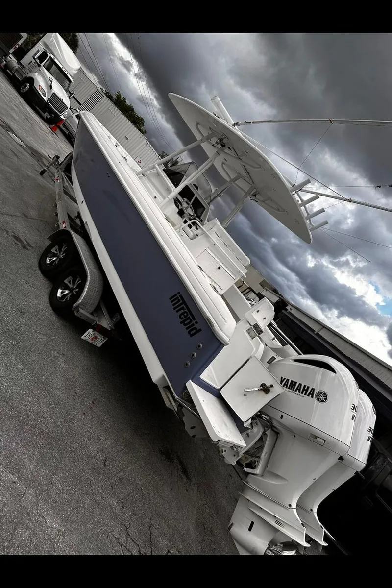 Slide: The Image of 2004 Intrepid 300 Center Console boat with Yamaha engines, parked under cloudy skies. - 7