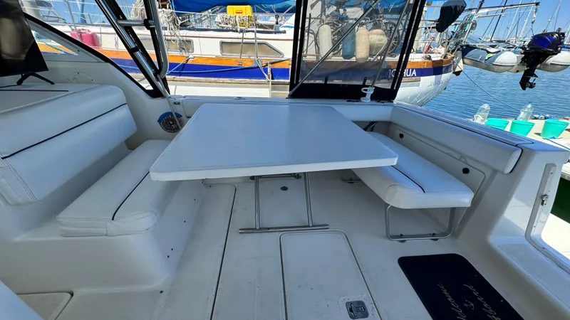 Slide: The Image of 2003 Tiara Yachts 2900 Coronet interior with white seating and table, docked at marina. - 2