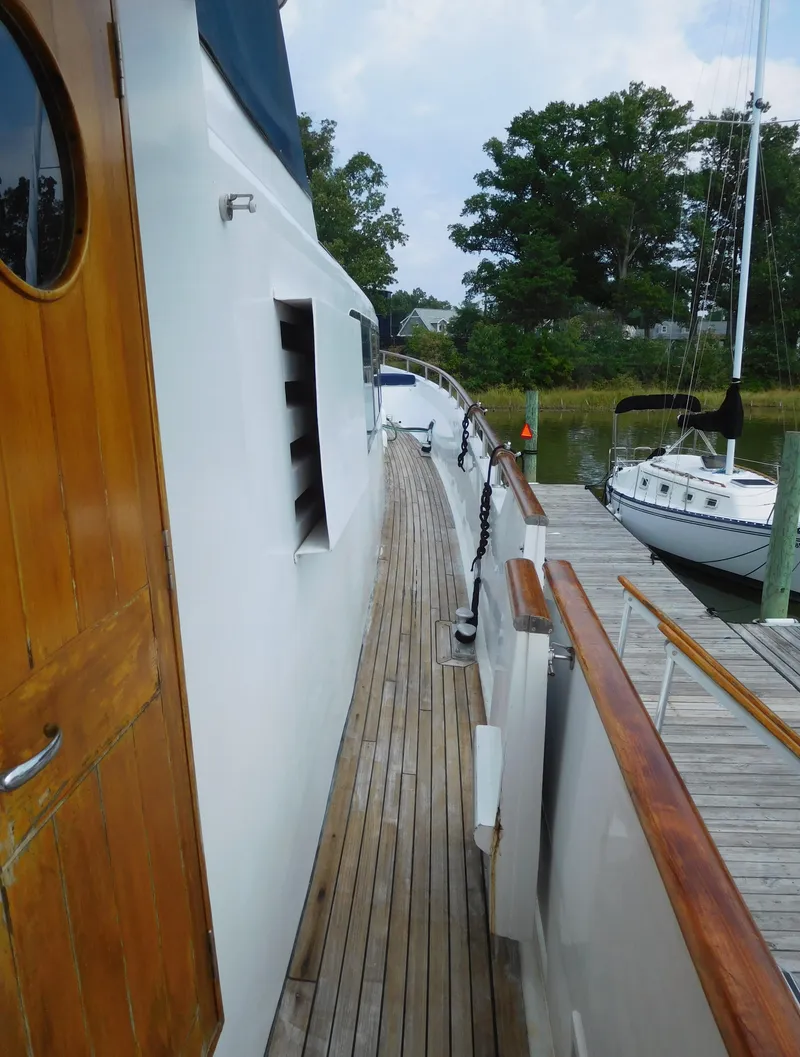 Slide: The Image of 1983 Cheoy Lee 90 cockpit motor yacht docked, featuring wooden deck and sleek design. - 10