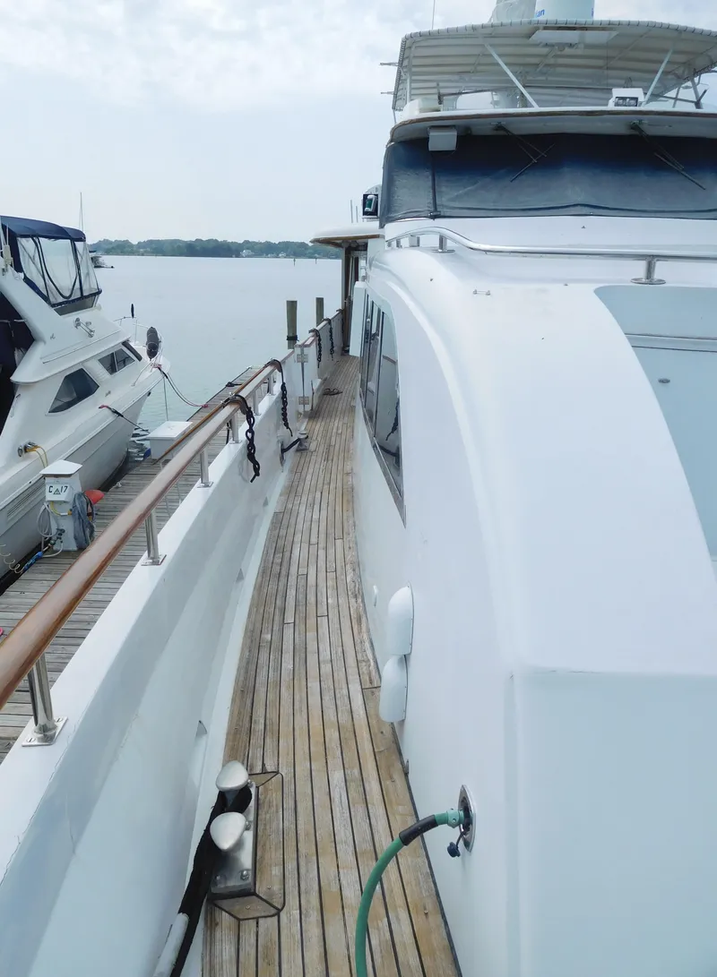 Slide: The Image of 1983 Cheoy Lee 90 cockpit motor yacht docked, showcasing sleek design and wooden deck. - 13