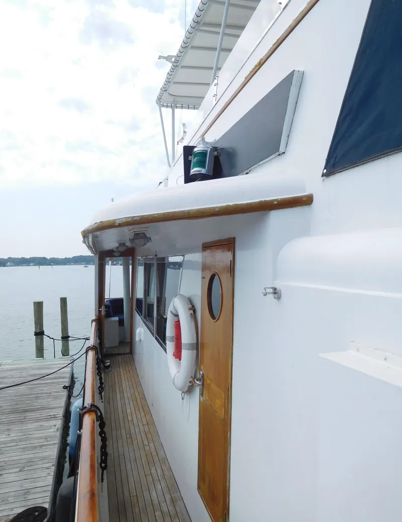 Slide: The Image of 1983 Cheoy Lee 90 cockpit motor yacht docked, side view with wooden accents. - 14