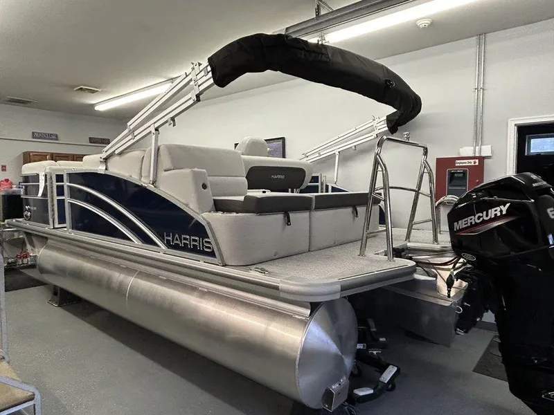 Slide: The Image of 2024 Harris Cruiser 190 pontoon boat with Mercury engine in a showroom. - 2