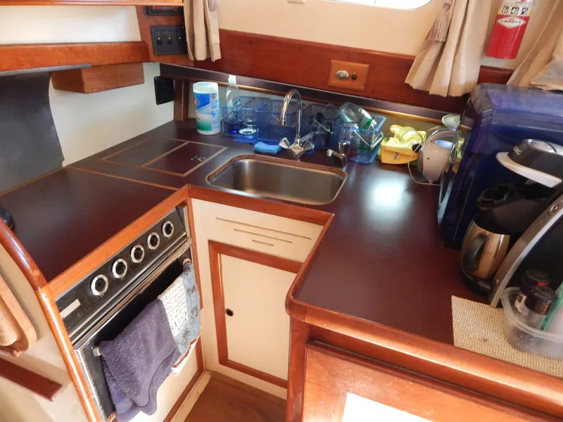 Slide: The Image of Compact kitchen area in a 1963 Grand Banks 35 Chantyman boat, featuring a sink and appliances. - 3