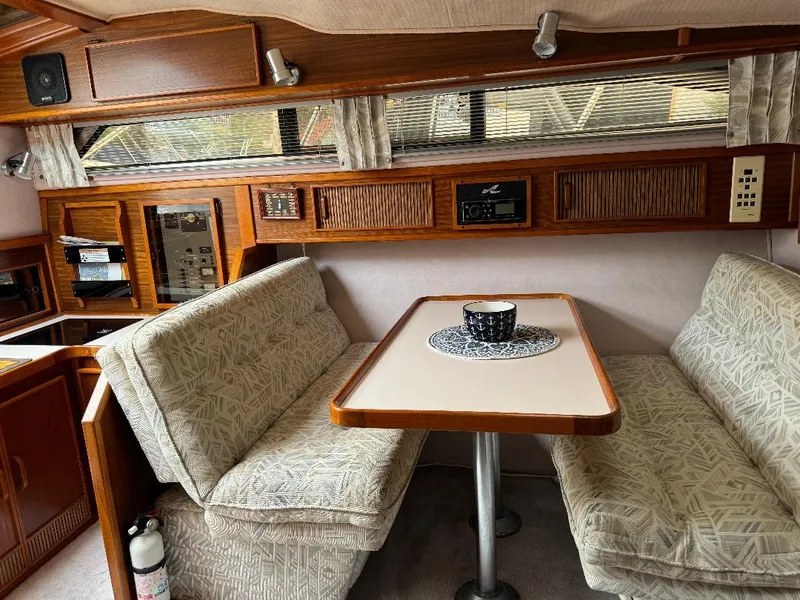 Slide: The Image of 1987 Sea Ray 340 Express Cruiser interior with dining area and cushioned seating. - 10