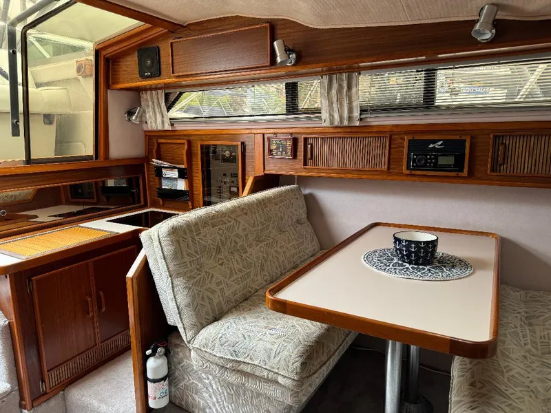 Slide: The Image of 1987 Sea Ray 340 Express Cruiser interior with dining area, wood cabinetry, and seating. - 11