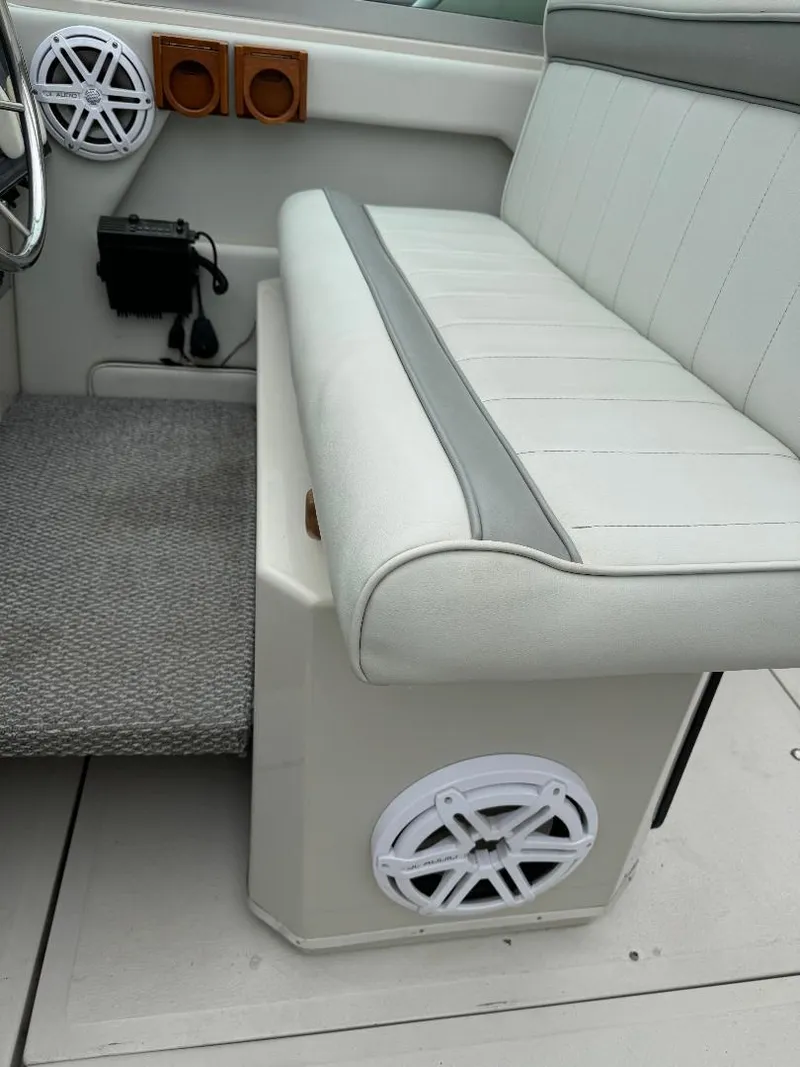 Slide: The Image of 1987 Sea Ray 340 Express Cruiser interior with white seating and speaker system. - 13