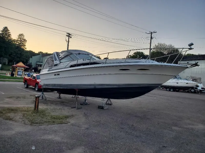 Slide: The Image of 1987 Sea Ray 340 Express Cruiser on stands in a parking lot at sunset. - 2