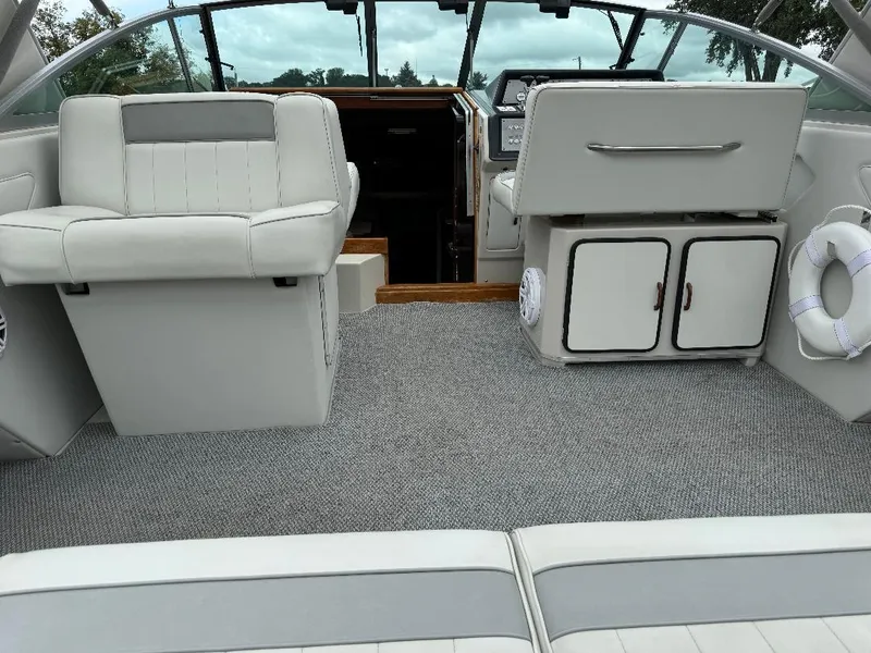 Slide: The Image of 1987 Sea Ray 340 Express Cruiser interior with gray seating and carpet, featuring a helm and storage. - 21