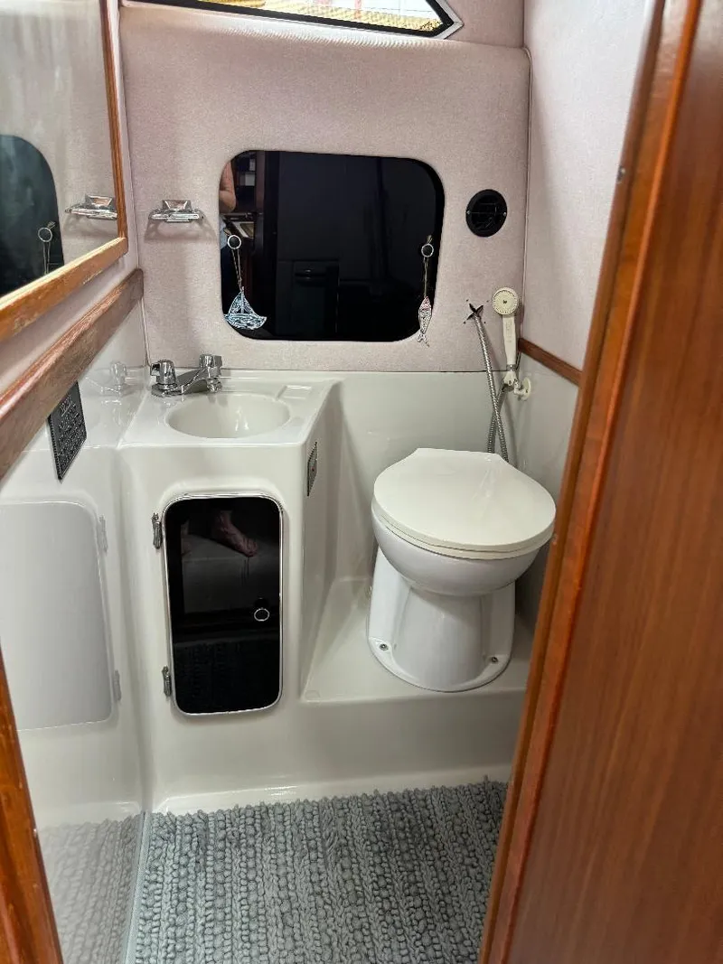 Slide: The Image of 1987 Sea Ray 340 Express Cruiser bathroom with sink, toilet, and window. - 25