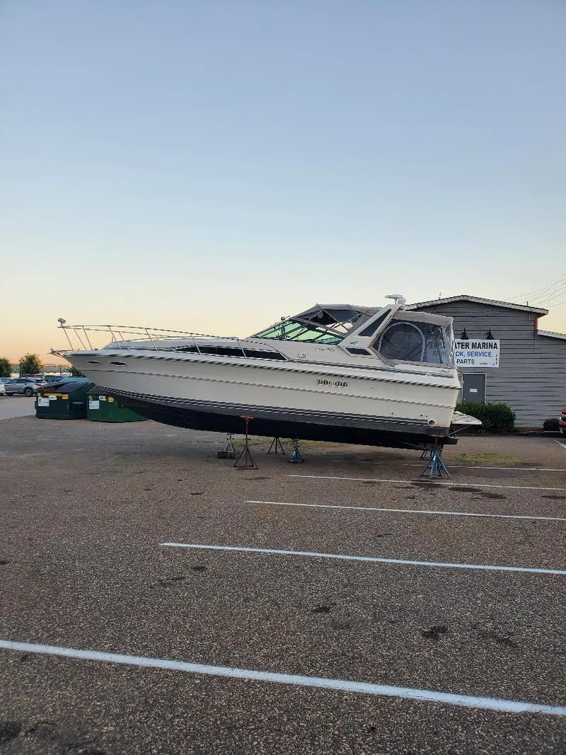 Slide: The Image of 1987 Sea Ray 340 Express Cruiser on stands in a parking lot. - 3