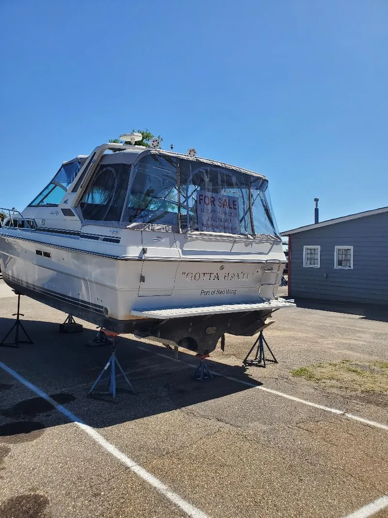 Slide: The Image of 1987 Sea Ray 340 Express Cruiser boat for sale, elevated on stands, clear sky background. - 4
