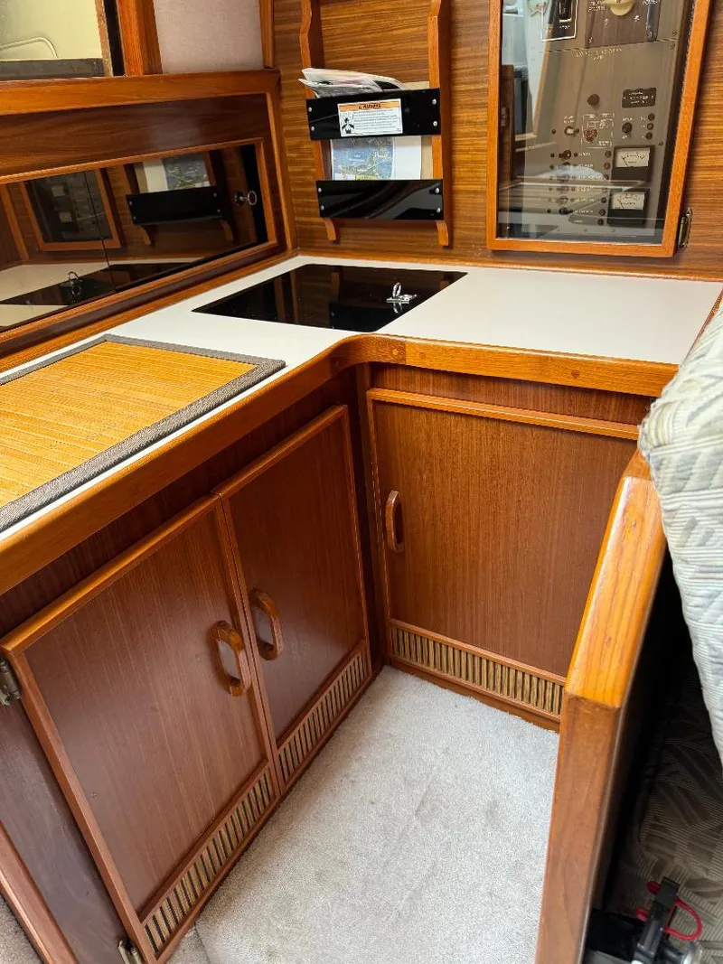 Slide: The Image of 1987 Sea Ray 340 Express Cruiser interior with wooden cabinetry and compact kitchen area. - 7