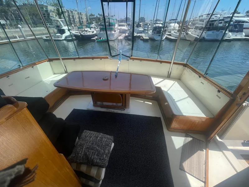 Slide: The Image of 1979 Hatteras 43 Motor Yacht interior with seating, table, and marina view. - 13