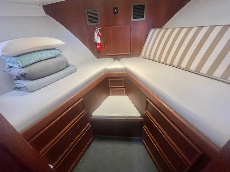 Slide: The Image of 1979 Hatteras 43 Motor Yacht cabin with twin beds, striped cushions, and wooden storage drawers. - 17