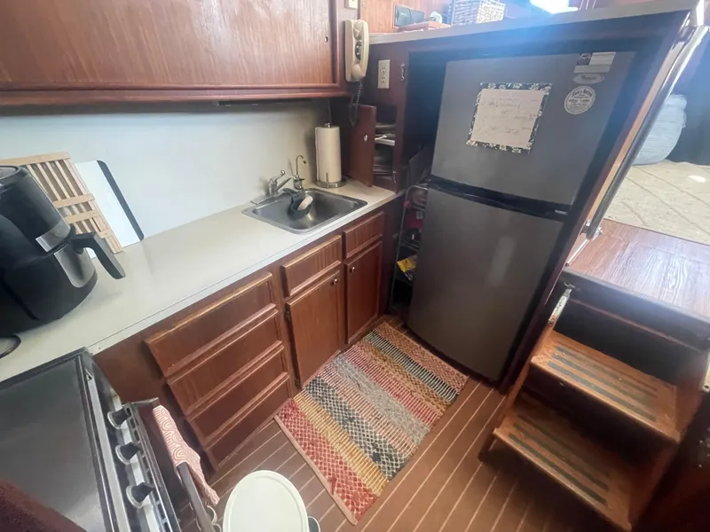 Slide: The Image of 1979 Hatteras 43 Motor Yacht kitchen with wooden cabinets, sink, and refrigerator. - 19