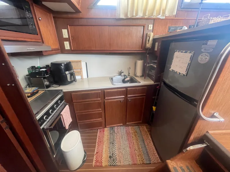 Slide: The Image of 1979 Hatteras 43 Motor Yacht kitchen with appliances, wooden cabinets, and colorful rug. - 20