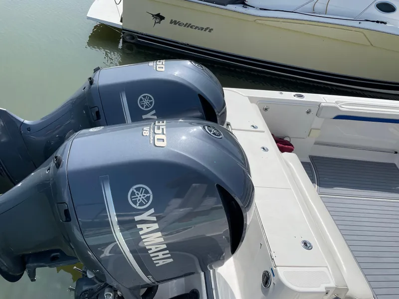 Slide: The Image of Twin Yamaha engines on a 2015 Wellcraft 35 Scarab boat, docked in calm waters. - 16