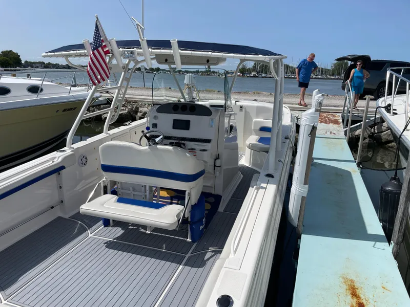 Slide: The Image of 2015 Wellcraft 35 Scarab boat docked, featuring a spacious deck and American flag. - 18
