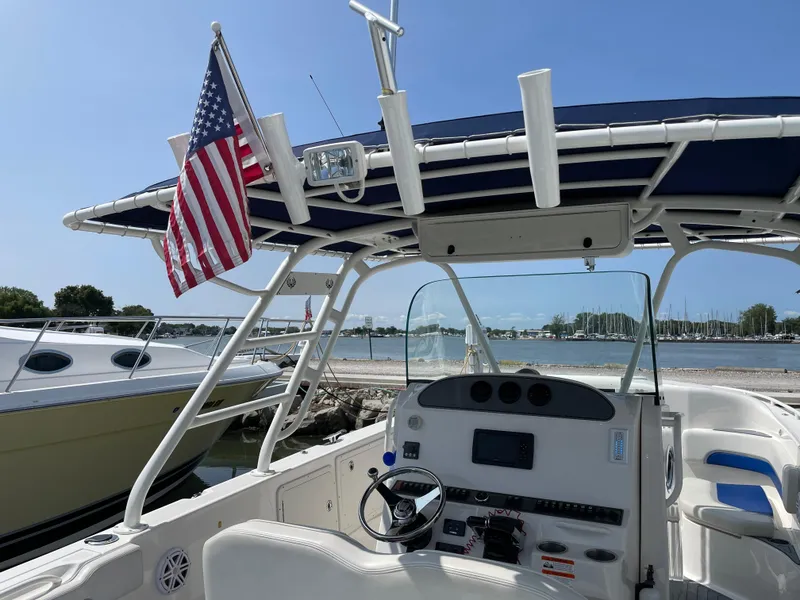 Slide: The Image of 2015 Wellcraft 35 Scarab boat with American flag, docked by a serene waterfront. - 25