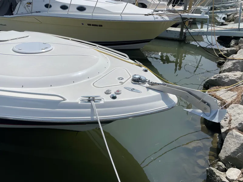 Slide: The Image of 2015 Wellcraft 35 Scarab boat docked, featuring sleek white design and anchor. - 7