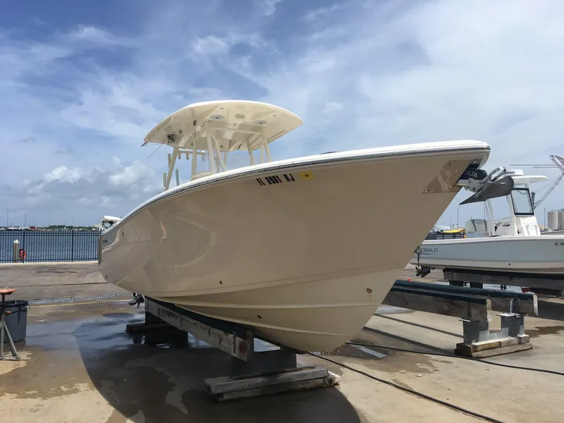 Slide: The Image of 2017 Cobia 296 CC boat on dock, clear sky background. - 1