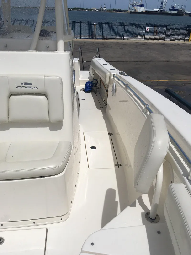 Slide: The Image of 2017 Cobia 296 CC boat interior with white seating and coastal view. - 12