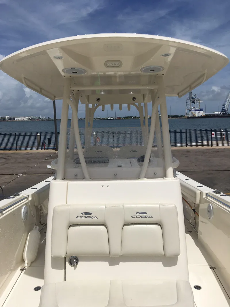 Slide: The Image of 2017 Cobia 296 CC boat docked by the waterfront under a clear sky. - 13