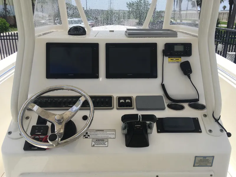 Slide: The Image of 2017 Cobia 296 CC boat dashboard with dual screens and steering wheel. - 14