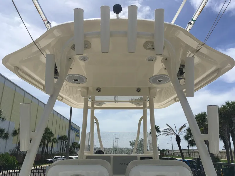 Slide: The Image of 2017 Cobia 296 CC boat, view of T-top and rod holders under clear sky. - 15