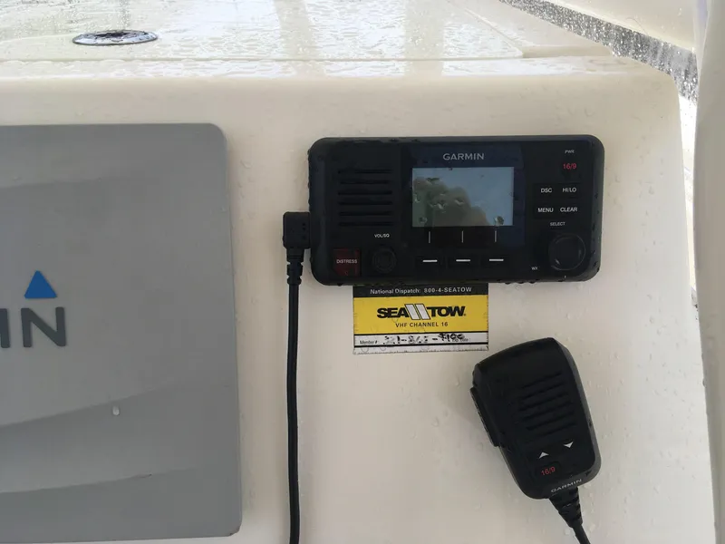 Slide: The Image of Garmin marine radio on 2017 Cobia 296 CC boat dashboard with Sea Tow sticker. - 9