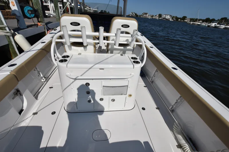 Slide: The Image of 2016 Sportsman Open 312 Center Console boat interior with seating and storage, docked by the water. - 5