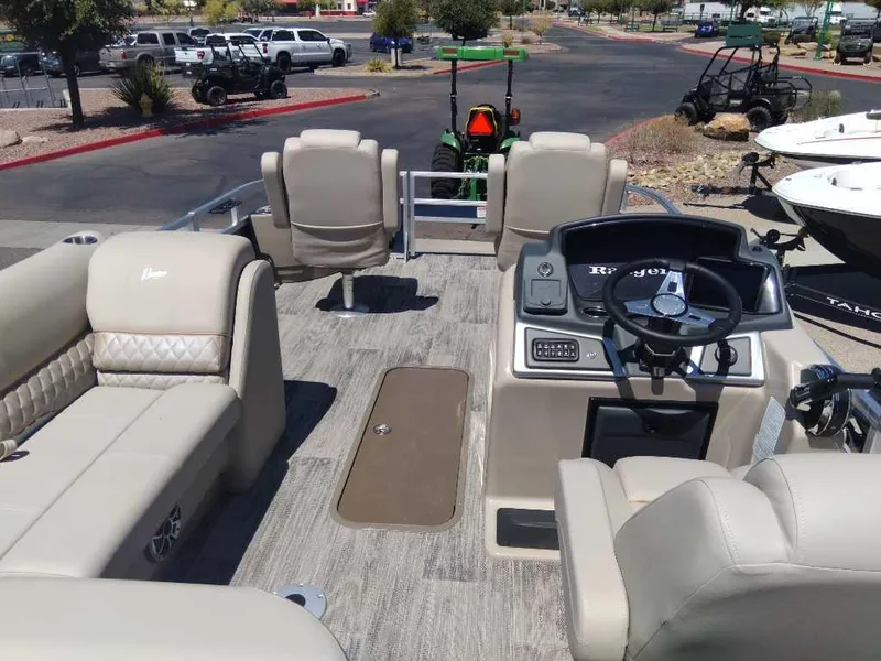 Slide: The Image of 2024 Ranger Reata 223F pontoon boat interior with beige seating and steering console. - 5