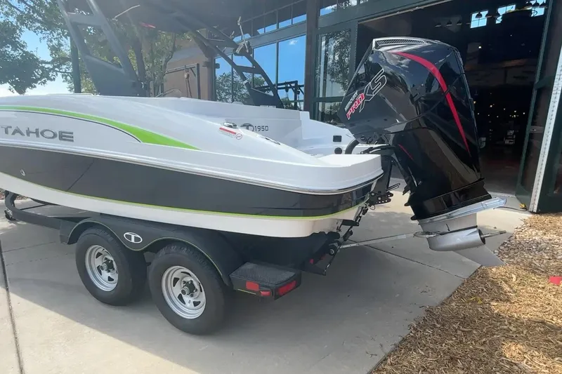 Slide: The Image of 2024 Tahoe 1950 boat on trailer with powerful outboard motor, parked outdoors. - 16