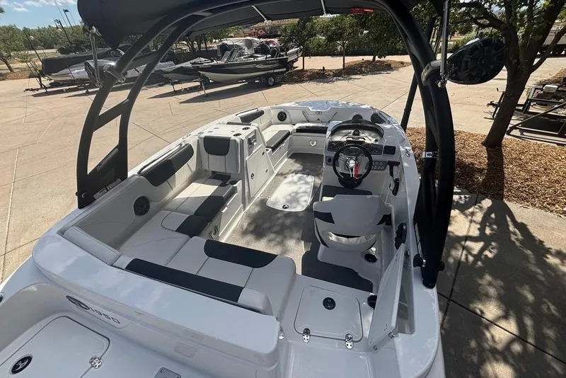Slide: The Image of 2024 Tahoe 1950 boat interior with seating and steering wheel, parked outdoors. - 6