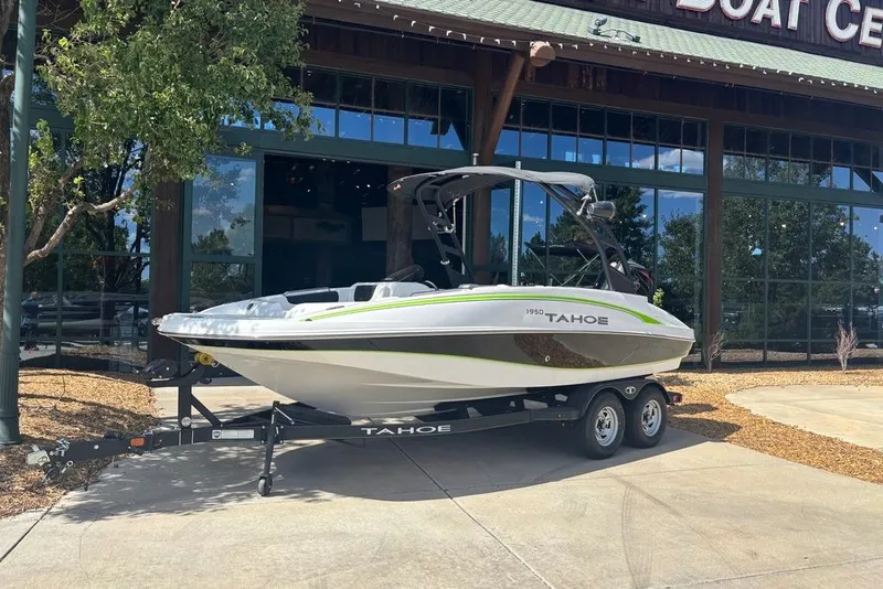 Slide: The Image of 2024 Tahoe 1950 boat on trailer outside a boat center, sunny day. - 1
