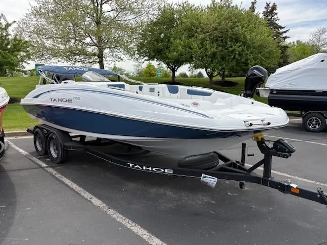 The Image of 2024 Tahoe 2150 boat on trailer in parking lot, surrounded by trees and other boats. - 0