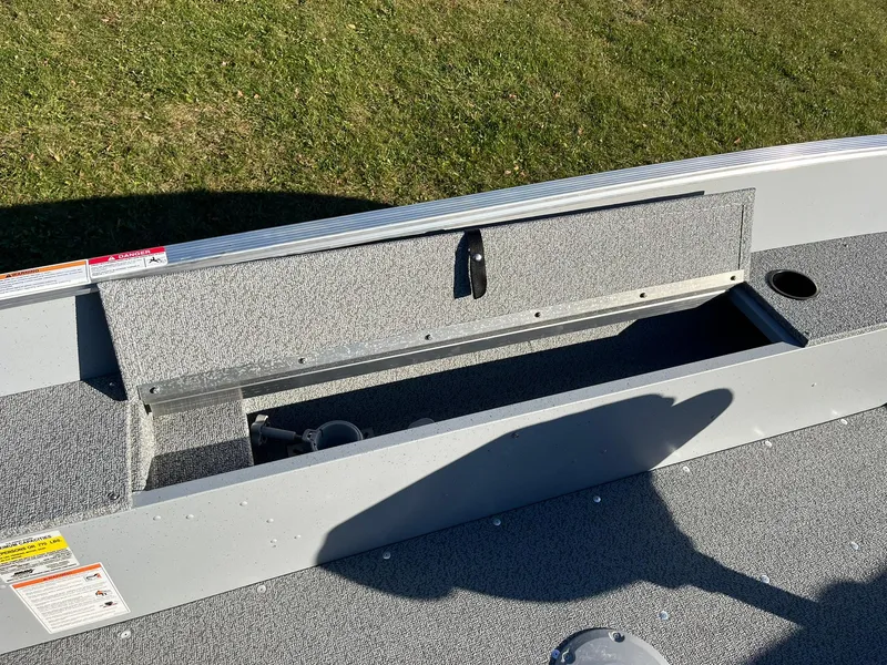 Slide: The Image of 2025 Lund 1600 Fury Tiller boat interior storage compartment on grassy background. - 14