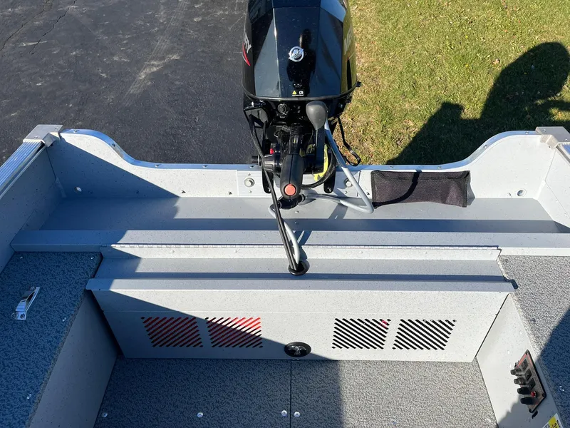 Slide: The Image of 2025 Lund 1600 Fury Tiller boat interior with motor, gray seating, and storage compartments. - 19