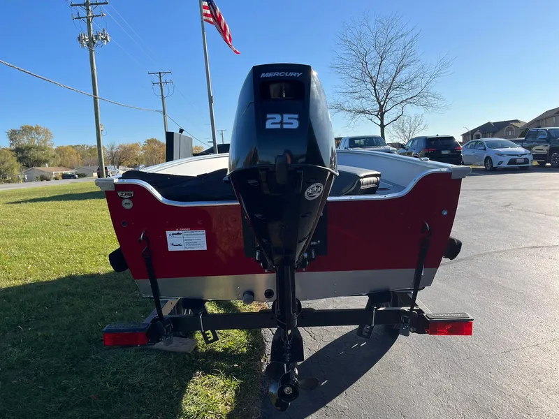Slide: The Image of 2025 Lund 1600 Fury Tiller boat with Mercury 25 engine, parked outdoors. - 3