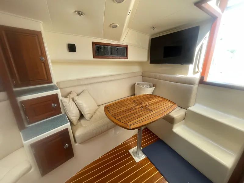 Slide: The Image of Interior of 2006 Carolina Classic 35 boat with wooden table and beige seating. - 16