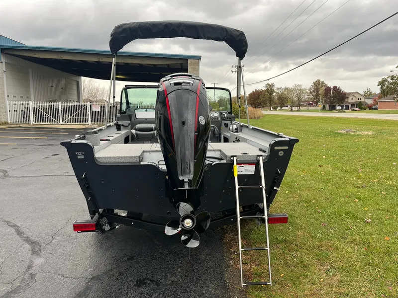 Slide: The Image of 2025 Lund 1775 Adventure Sport boat with outboard motor and ladder, parked outdoors. - 2