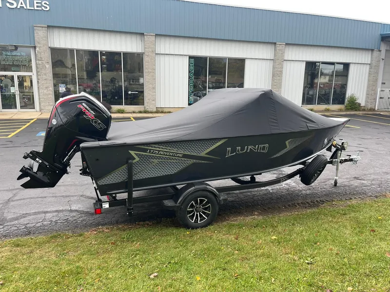 Slide: The Image of 2025 Lund 1775 Adventure Sport boat with cover on trailer, parked outside dealership. - 22