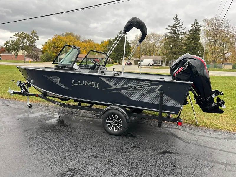 Slide: The Image of 2025 Lund 1775 Adventure Sport boat on trailer, parked outdoors on a cloudy day. - 3