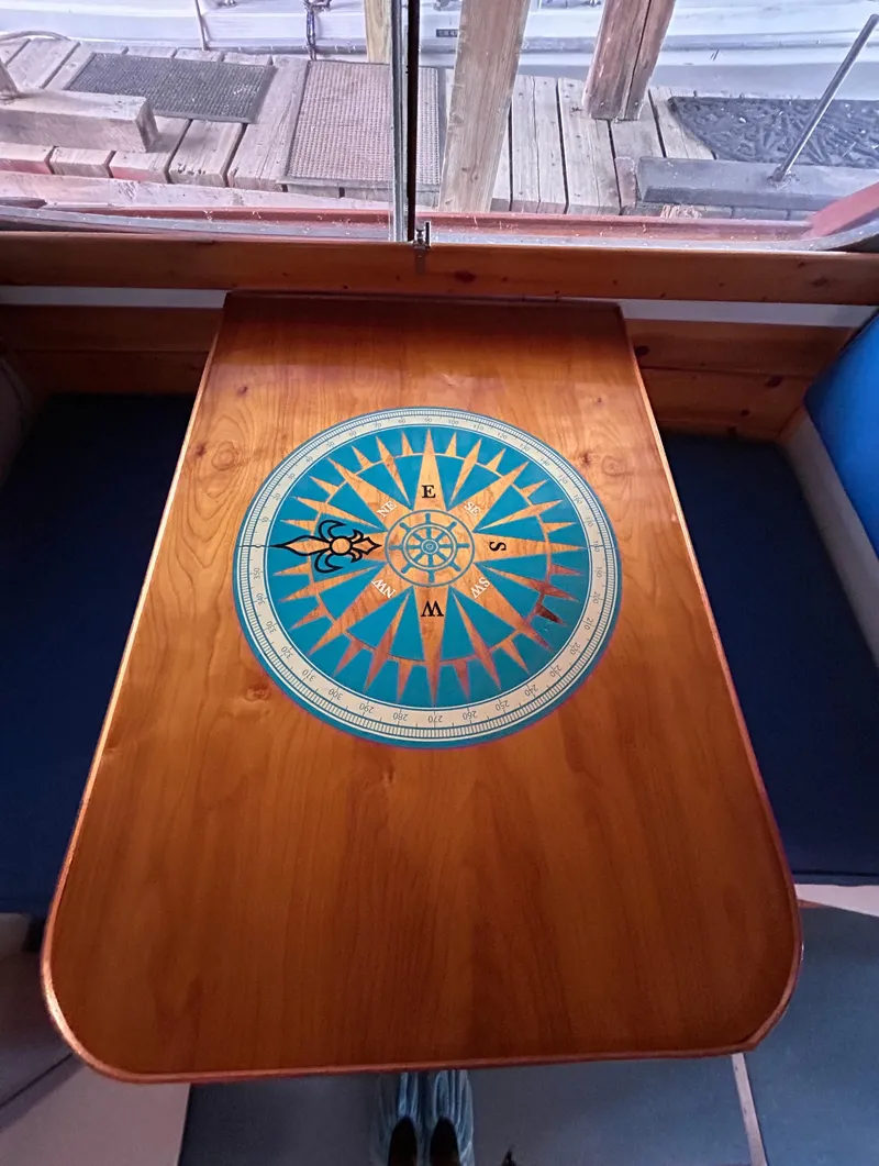 Slide: The Image of Wooden table with compass design on a 1954 Chris-Craft Commander 336 Express Cruiser. - 48
