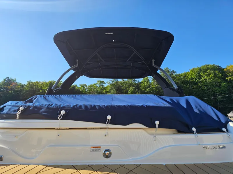 Slide: The Image of 2022 Sea Ray SLX 250 boat with blue cover and canopy, docked outdoors. - 32