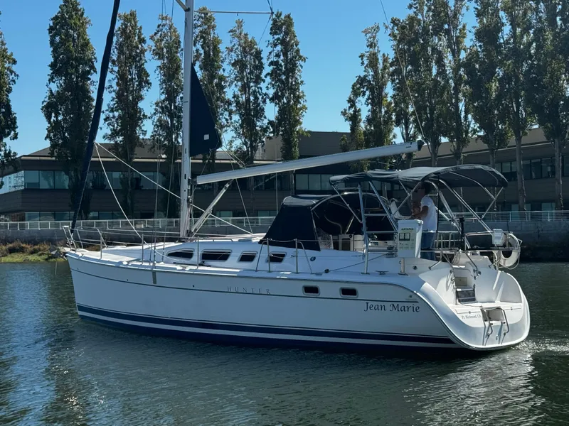 Slide: The Image of 2007 Hunter 41 sailboat on calm water, surrounded by trees and buildings. - 8